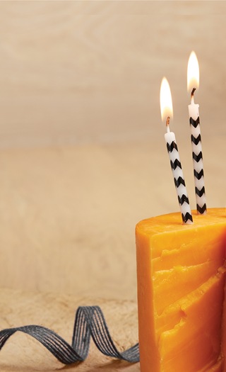 block of cheddar cheese with lit birthday candles