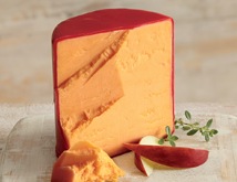 Cheddar Cheese Red wax-coated Cheddar Cheese with a slice displayed next to apple wedges